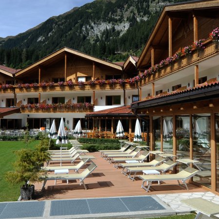 Hotel di montagna con terrazza, sedie a sdraio e fiori colorati.