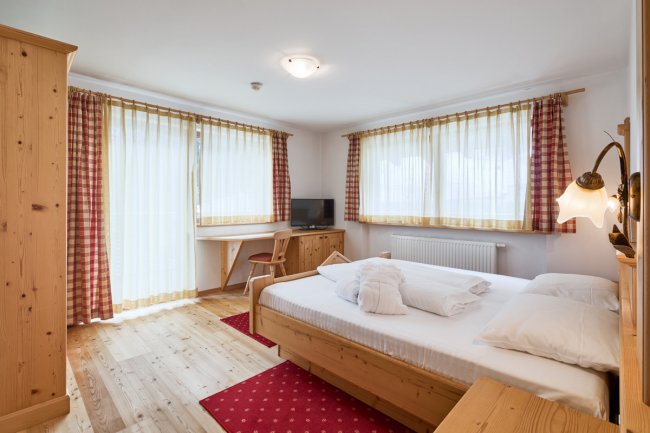 Camera d'albergo con arredamento in legno e finestre luminose.