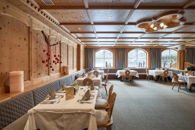 Sala da pranzo elegante con arredi in legno e tavole apparecchiate.