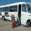 Tre bambini vicino a un piccolo autobus bianco.