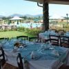 Tavoli apparecchiati con vista su piscina e giardino fiorito.