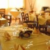 Una sala da pranzo con tovaglie gialle, bicchieri e tovaglioli piegati su tavoli apparecchiati.