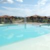 Piscina all'aperto con villette sullo sfondo e cielo parzialmente nuvoloso.