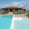 Una piscina con lettini e un edificio con tetto rosso sullo sfondo sotto un cielo nuvoloso.
