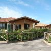 Edificio con tetto in tegole e giardino con recinzione in legno su una strada pavimentata.