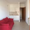 Interno con divano rosso e piccola cucina bianca a vista.