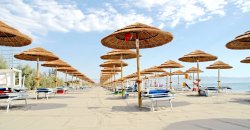 Spiaggia con ombrelloni di paglia e lettini.