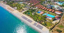 Vista aerea di un resort vicino al mare con piscine e ombrelloni sulla spiaggia.