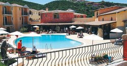 Un hotel con piscina esterna circondata da edifici colorati e persone sedute.