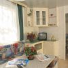 Interno di una casa mobile con divano colorato, tv, fiori e accessori decorativi.
