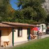 Bungalow in un campeggio, con tavolini all'aperto e ombrelloni colorati, circondati da alberi.
