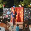 Uno spettacolo di clown all'aperto, con tende rosse e pubblico seduto su sedie.
