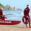 Due bagnini con divisa rossa e cappelli bianchi su una spiaggia sabbiosa vicino al mare.