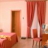 Camera da letto con tenda rossa, letto matrimoniale, sedia, scrivania e televisore.