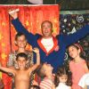 Gruppo di bambini e un uomo sorridente davanti a una tenda colorata.