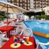 Piscina con tavoli rossi e cocktail colorati su prato.