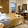 Una camera d'hotel con letto matrimoniale, vista mare e scrivania con computer.