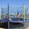 Bambini giocano su un trampolino elastico su una spiaggia soleggiata.