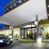 Ingresso di un hotel con tettoia bianca e un'auto parcheggiata davanti.