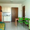 Un soggiorno luminoso con cucina, divano verde, tavolo e sedie verdi.