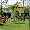 Giardino con prato, un edificio e alcune persone vicino a un'altalena.