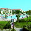 Piscina affollata con lettini e ombrelloni, circondata da prati e edifici residenziali.