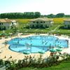 Ampia piscina circondata da sdraio e villette, immersa nel verde.