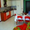 Cucina moderna con tavolo apparecchiato, sedie rosse e divano colorato.