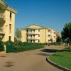 Complesso residenziale con giardini e strada pedonale, cielo blu.