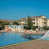 Una grande piscina con scivoli, lettini e persone che si godono il sole.