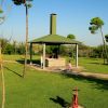 Giardino verde con tettoia, barbecue e due bambini; uno va in bici.