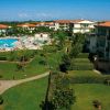 Complesso residenziale con piscina e giardini curati, visti dall'alto, in una giornata soleggiata.