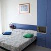 Camera da letto minimalista con letto matrimoniale, armadio blu e quadro sulla parete.