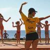 Gruppo fa esercizi con istruttrice sulla spiaggia.