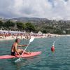 Persona su kayak rosso vicino alla spiaggia affollata.