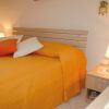Un letto matrimoniale con copriletto arancione e cuscini su un comodino con lampada.