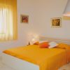 Stanza luminosa con un letto matrimoniale arancione e tende coordinate, quadri alle pareti.