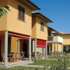 Villette con terrazze, sedie e tavoli sotto tende rosse su prati verdi.