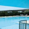 Grande piscina all'aperto circondata da lettini e ombrelloni.