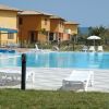 Piscina all'aperto con lettini bianchi e villette colorate sullo sfondo.