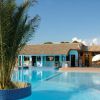 Piscina con palma centrale, vista su edificio azzurro e villette.