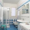 Bagno con piastrelle blu, doccia, lavatrice e servizi igienici.