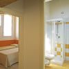 Camera da letto e bagno con doccia, divisi da un corridoio.