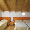 Tre letti singoli con testiere arancioni in una stanza con soffitto in legno.