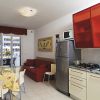 Cucina abitabile con tavolo apparecchiato, divano rosso e terrazzo.