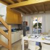Cucina e zona pranzo con soffitto in legno e porta finestra su terrazzo.