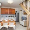 Cucina moderna con arredi arancioni, tavolo apparecchiato e scala in legno.