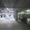 Parcheggio sotterraneo con auto parcheggiate e uscita in lontananza.