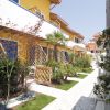 Un complesso residenziale colorato con giardini, pergolati di legno e vialetti.