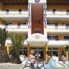 Facciata di un edificio giallo con balconi, due persone con biciclette davanti all'entrata.